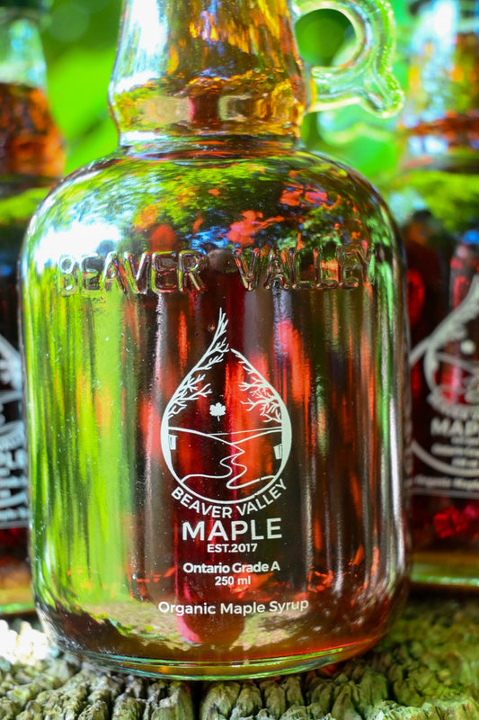 Close-up of a Beaver Valley Maple bottle with vivid green and red reflections — estate-bottled single-origin maple syrup from the Niagara Escarpment