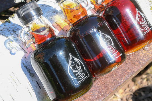 Beaver Valley Organic Maple Syrup bottles arranged outdoors on a weathered white bench